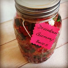 a jar filled with gummy bears sitting on top of a wooden floor next to a pink sticker