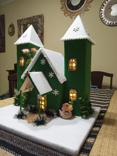 a green house with snow on the roof and windows in front of it is lit up at night