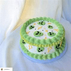 a cake with green icing and white frosting on it's side, sitting on top of a white cloth