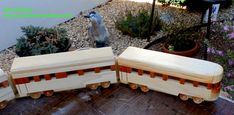 three wooden toy train cars sitting on top of a wood floor next to potted plants