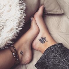 two people laying on top of a bed with their feet crossed and tattoos on them