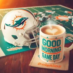 a miami dolphins football helmet sitting on top of a table next to a coffee cup