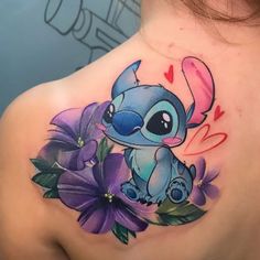 the back of a woman's shoulder with a cartoon character on it and flowers