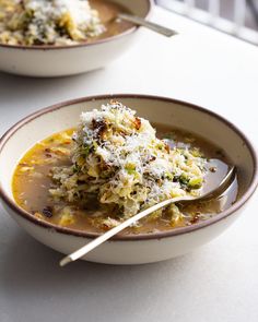 two bowls filled with soup on top of a white table next to another bowl full of food