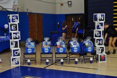 some chairs are set up on the basketball court with bags and balls in front of them