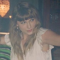 a woman with long hair and bangs posing for a photo in front of a wall