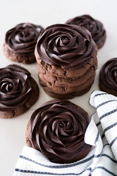 chocolate cookies with chocolate frosting on top and white napkins next to each other