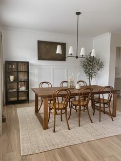 a dining room table with six chairs and a vase on the rug in front of it