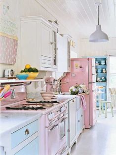 a kitchen filled with pink appliances and lots of counter space next to a dining room table