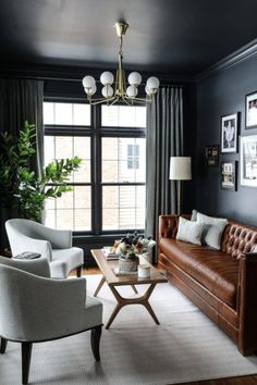 a living room with black walls and leather furniture