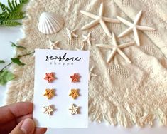 someone is holding three star shaped earrings in front of a card with the words seashore shoppe written on it