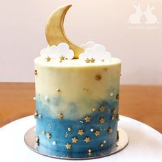 a blue and white cake with gold stars on the top is decorated with a crescent moon