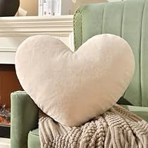 a heart shaped pillow sitting on top of a green chair in front of a fireplace