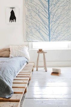 a bed sitting on top of a wooden pallet in a bedroom next to a window