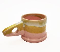 a pink and yellow coffee cup sitting on top of a white table