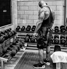 a man standing in front of a row of dumbbells with his back to the camera