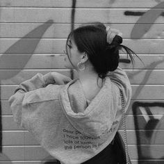 a woman standing in front of a graffiti wall with her back turned to the camera