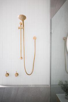 a shower head and hand shower in a white tiled bathroom with gold fixtures on the wall