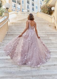 a woman in a pink dress is walking down some stairs with her back to the camera