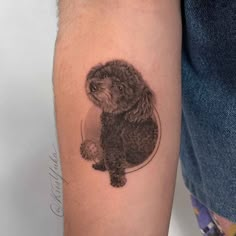 a small black and white poodle tattoo on the right arm, with a ball in it's paws