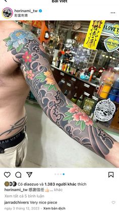 a man with a tattoo on his arm and chest standing in front of a bar