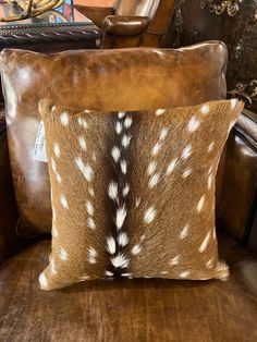 a brown leather chair with two pillows on it and a deer print pillow in the back