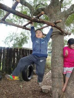 two children are playing in the tree with tire tires and climbing bars for balances