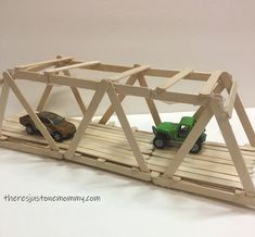 two toy cars on a wooden bridge that is made out of plywood planks