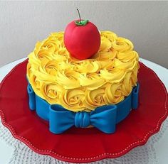 a cake with yellow icing and a red apple on top, sitting on a plate