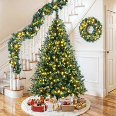 a christmas tree with lights and presents under the banister