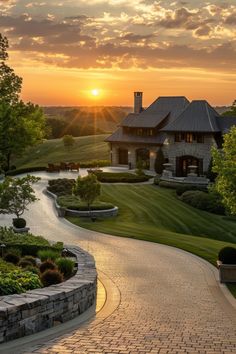 the sun is setting in front of a large house with a driveway leading to it