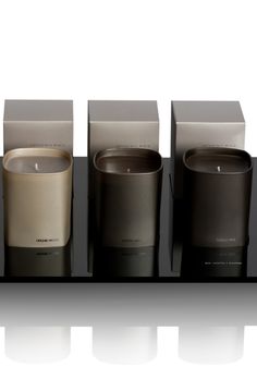 four candles are lined up next to each other on a black tray with white background