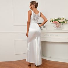 a woman standing in front of a piano wearing a white dress with lace on the back