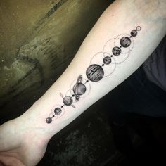 a person with a tattoo on their arm that has planets and stars in the middle