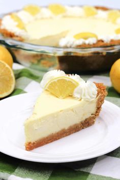 a slice of lemon pie on a white plate next to sliced lemons and a glass dish