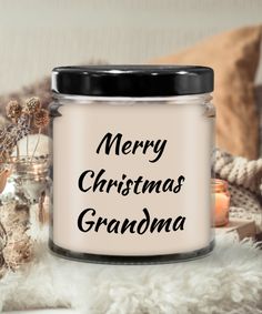 a glass jar with the words merry christmas grandma on it next to candles and other decorations