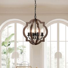 a chandelier hanging from the ceiling in a room with arched windows and potted plants