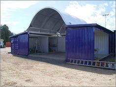 two blue shipping containers sitting in the middle of a parking lot next to a building