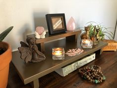 a wooden table topped with candles next to a potted plant and an angel figurine