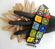 a close up of a bracelet on a mannequin with flowers in the background