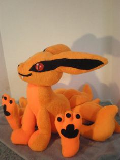 an orange stuffed animal sitting on top of a table next to other stuffed animals and toys