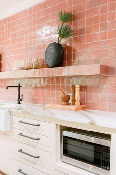 a kitchen with white cabinets and pink tiles on the wall, along with an oven