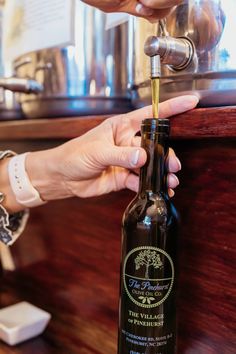 a person is pouring olive oil into a bottle