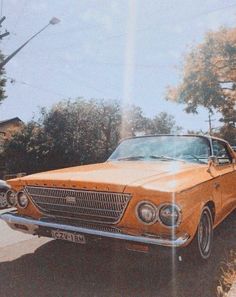 an old yellow car is parked on the side of the road