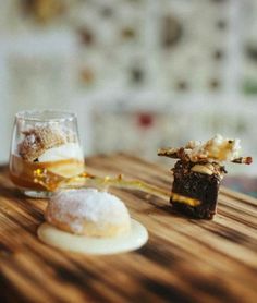 two desserts sitting on top of a wooden table next to a glass filled with liquid