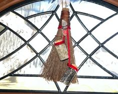 a broom hanging from the side of a stained glass window with red ribbon around it