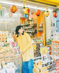 a woman standing in front of a store filled with goods