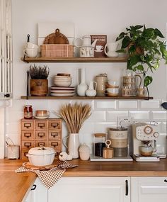 a kitchen with white cabinets and shelves filled with dishes, coffee mugs and other items