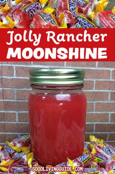 a mason jar filled with jelly rancher moonshine sitting in front of a pile of candy