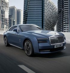 a blue car driving down the road in front of tall buildings